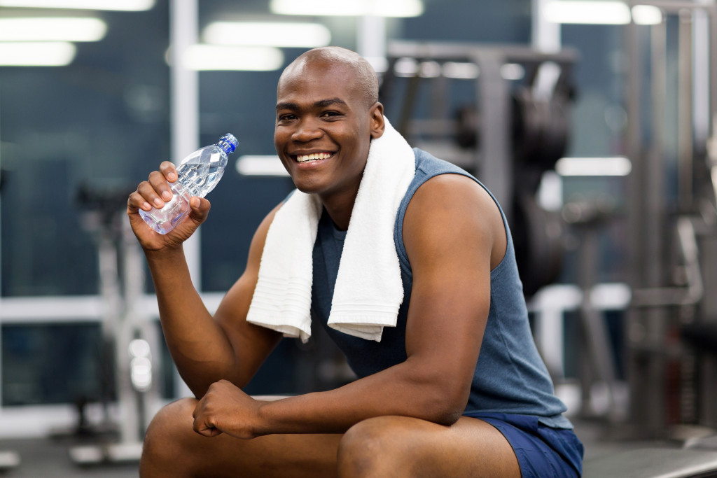 man in gym holding a bottle of water smiling