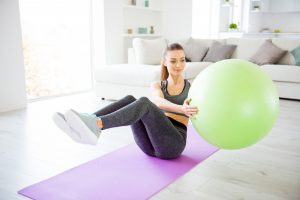 woman using a yoga mat and ball to exercise