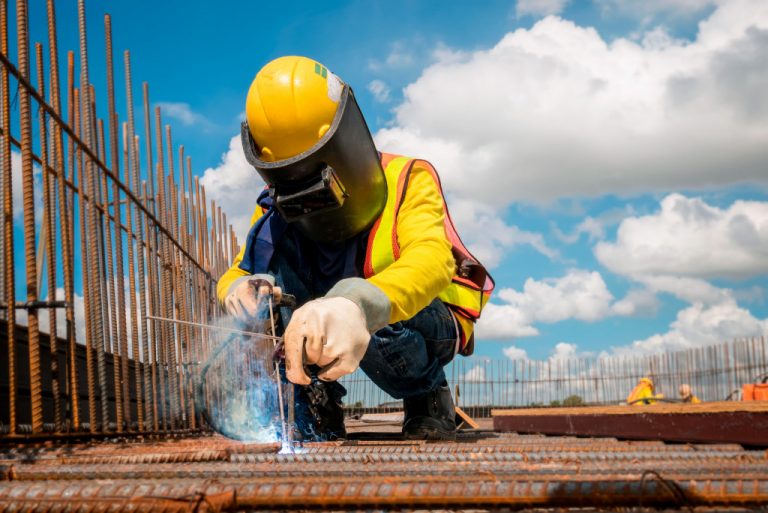 construction worker wearing ppc while welding metals on an unfinished building