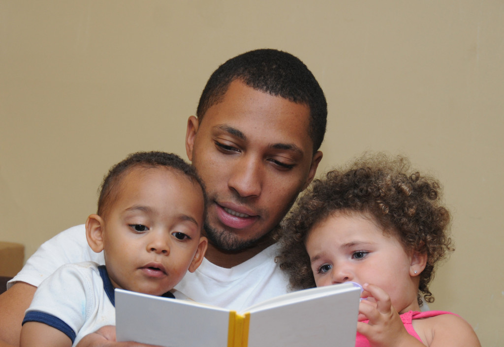 father reading a book to his children