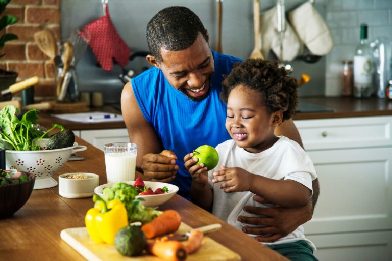 father and daughter holding fruits