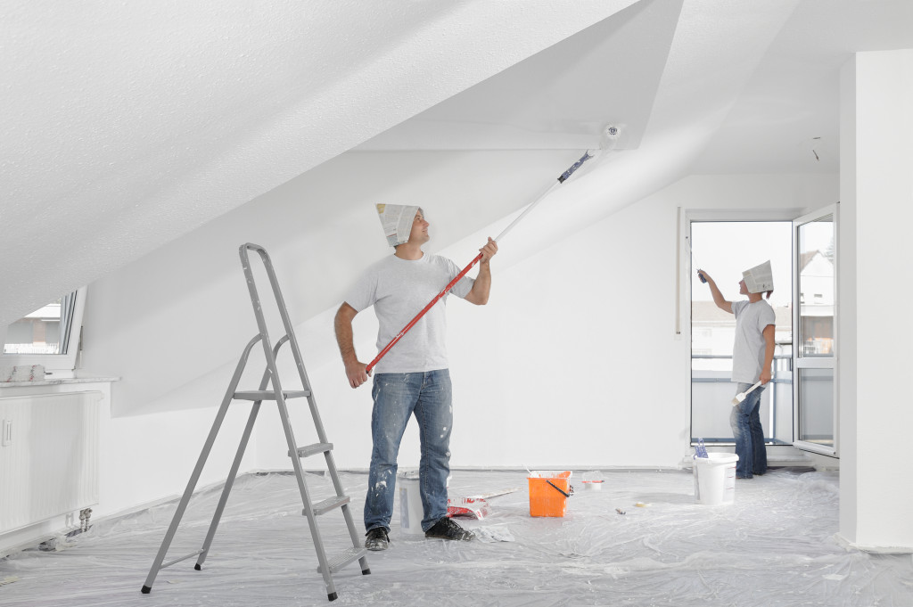 A man painting the walls with white color