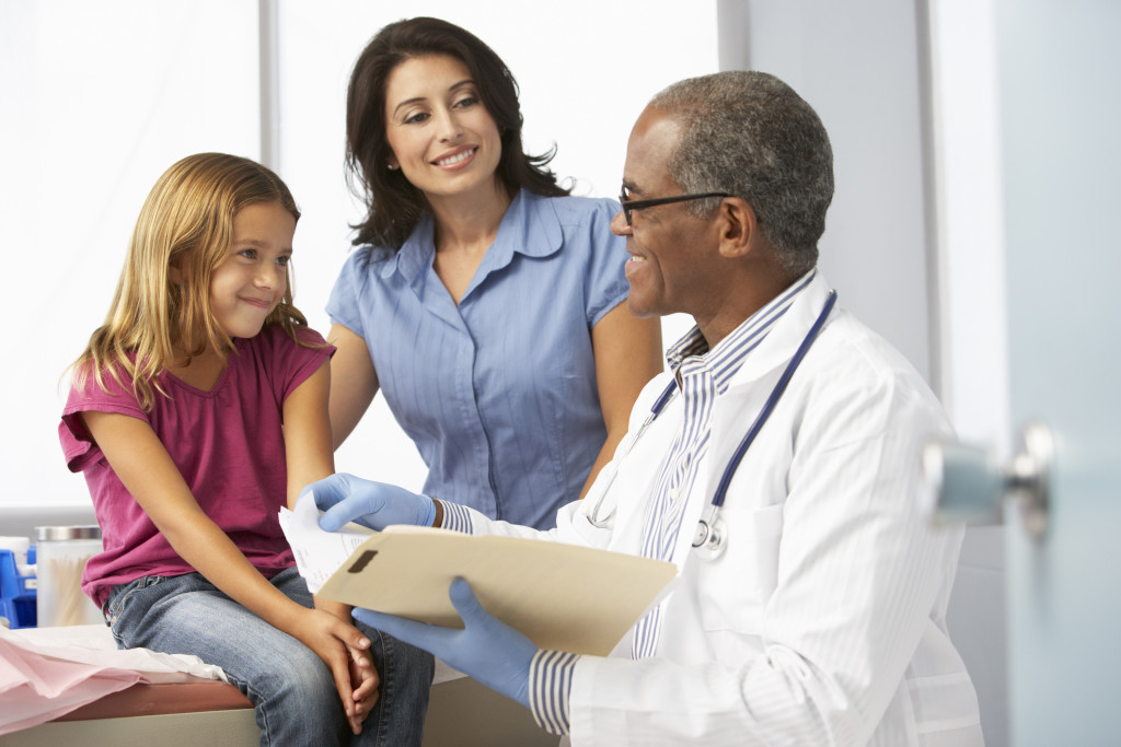 A young girl getting a check up from a doctor with her mother in the clinic