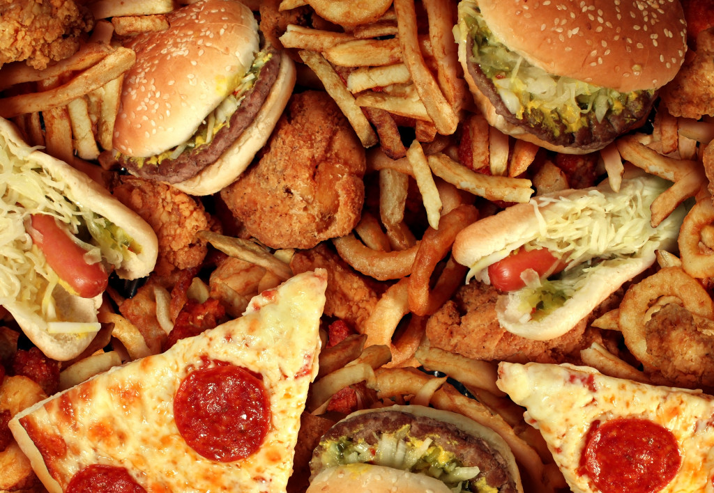 A pile of burgers, pizzas, hotdog, fries