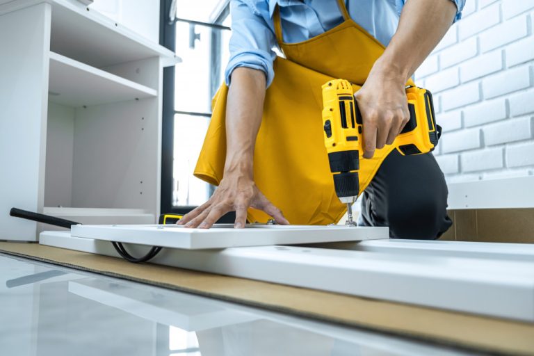 A man drilling a hole to a cabinet doing renovation at home