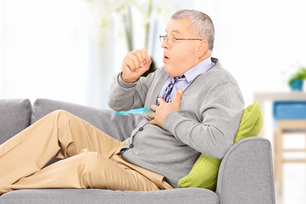 mature man coughing at home concept of chronic disease