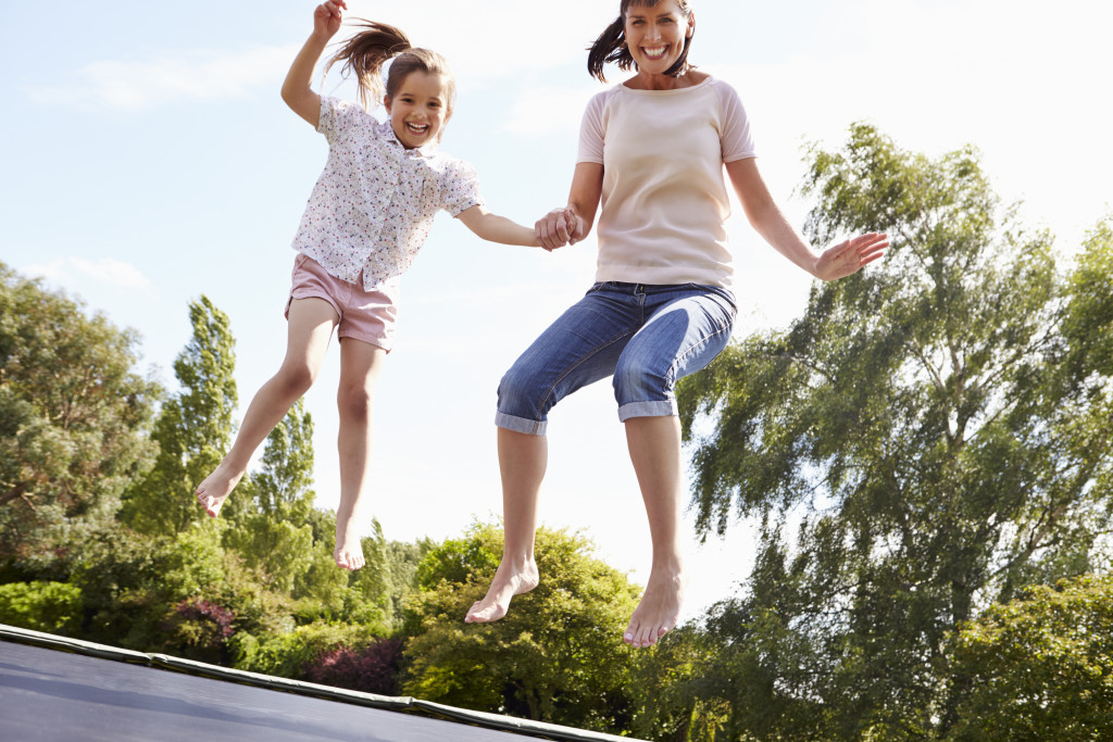 A mother and daughter jumping on an outdoor trampoline