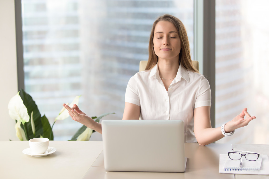 A woman at work taking time to relax and meditate at her desk