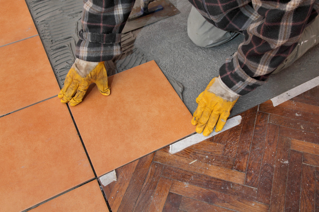 A man laying tiles inside a home