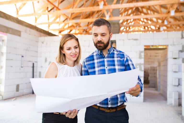 young couple looking at house plan in a home construction site