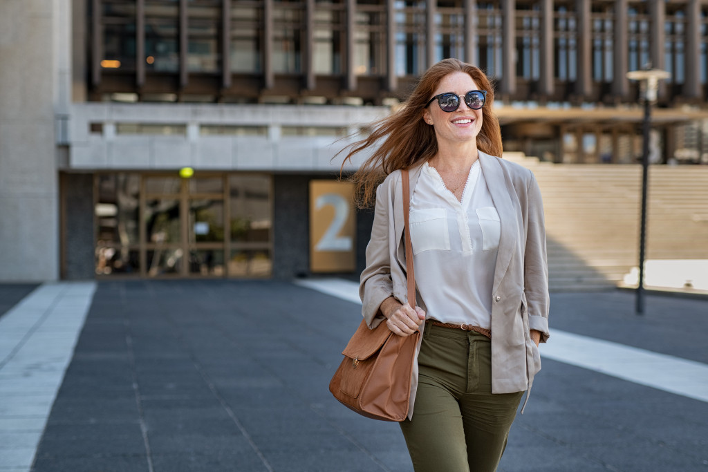 A stylish woman walking while wearing sunglasses on a sunny day