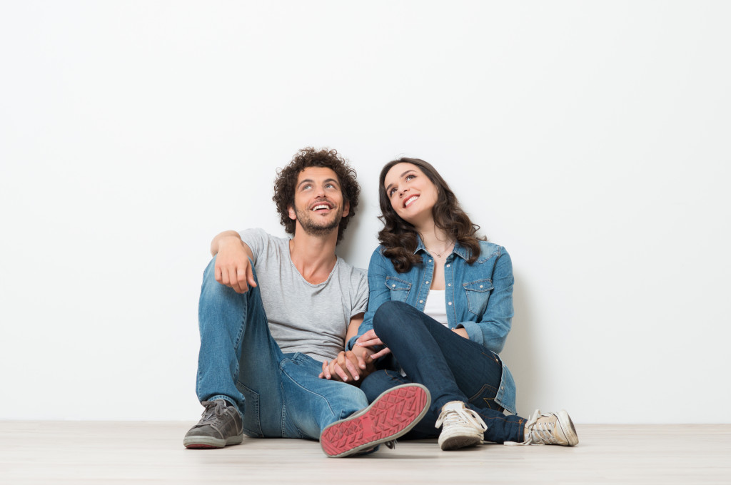 happy couple sitting in floor against white wall