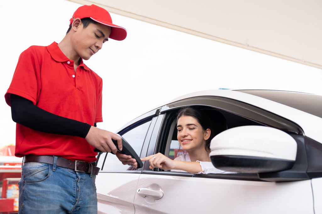 A gasoline station staff assisting a woman paying by credit card