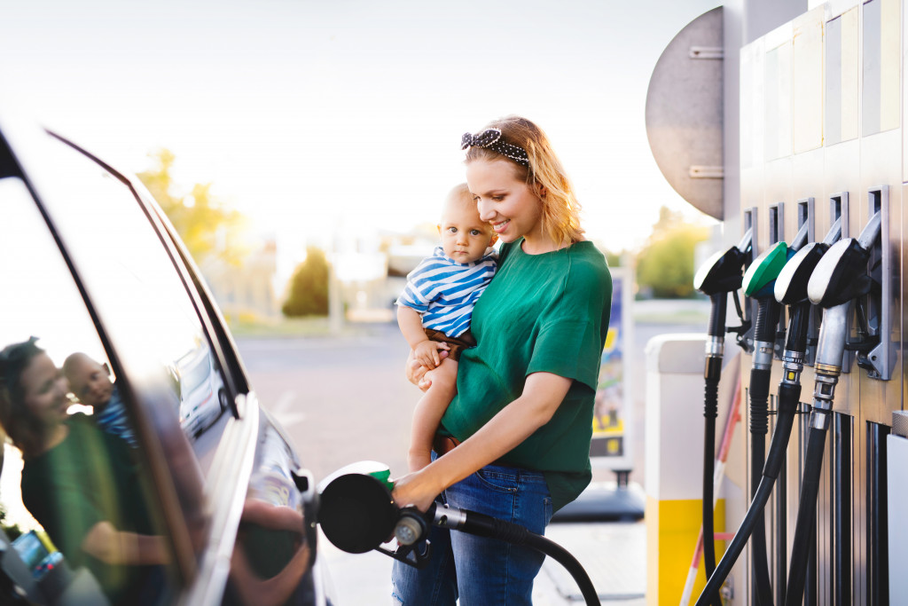 A woman with child pumping gas into her car