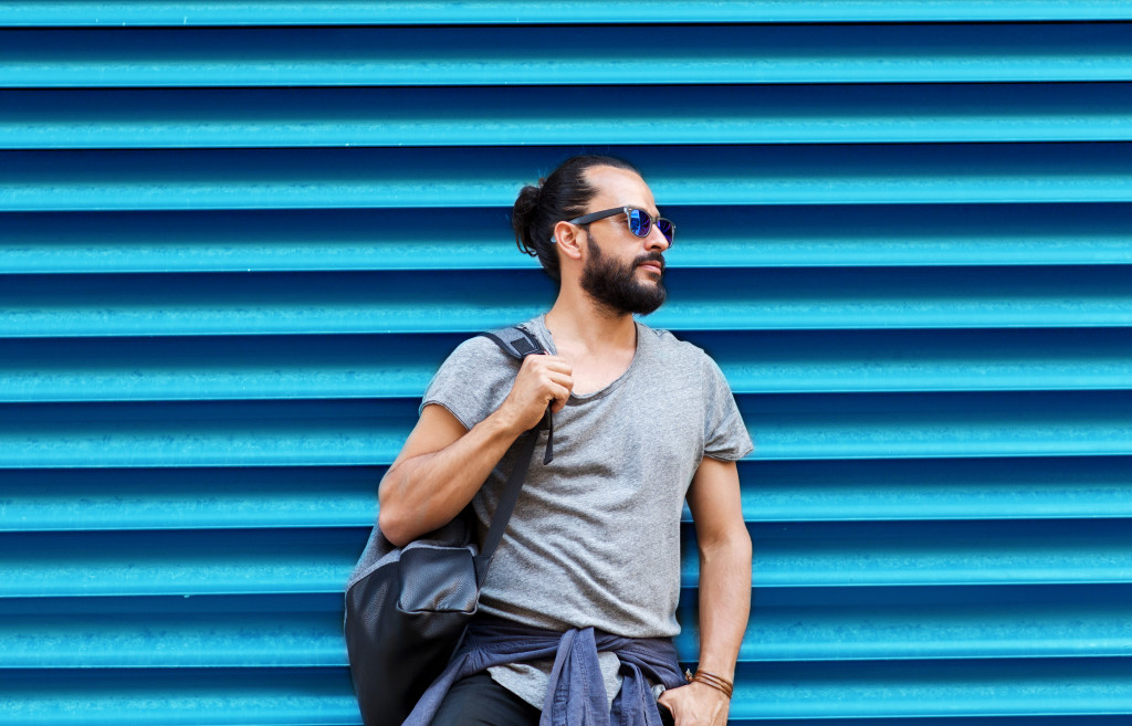 A man posing in front of a ribbed blue wall