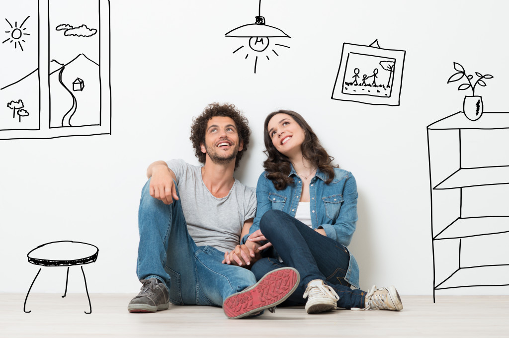 A couple sitting on the floor while dreaming of their new home