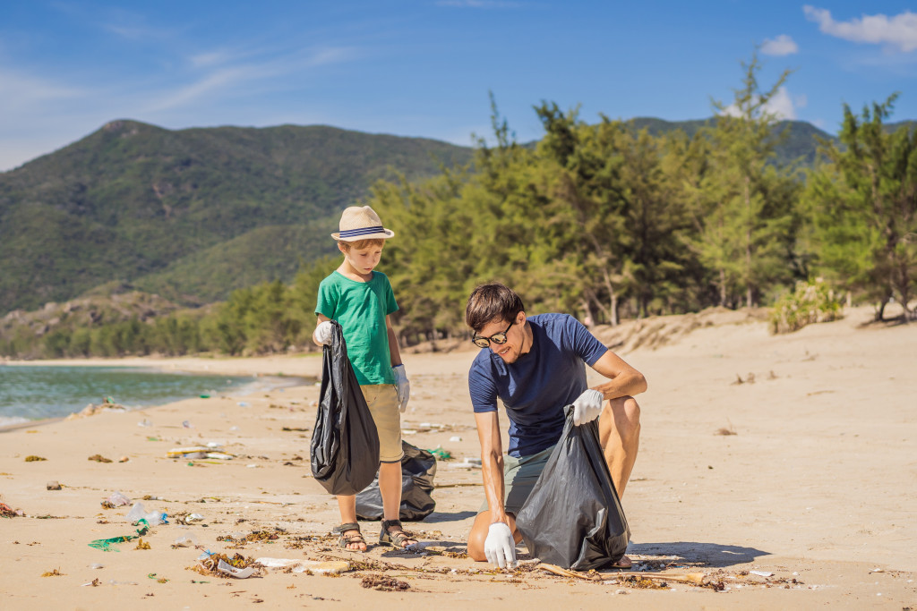 a man and a child picking up litter on the beach