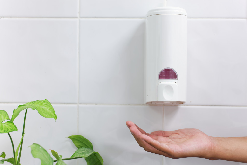 soap dispenser with hand in bathroom