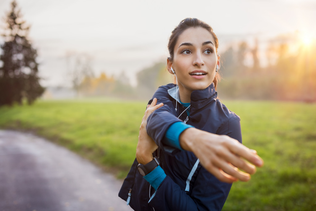 woman looking back and smiling while stretching before a run outdoors in the morning