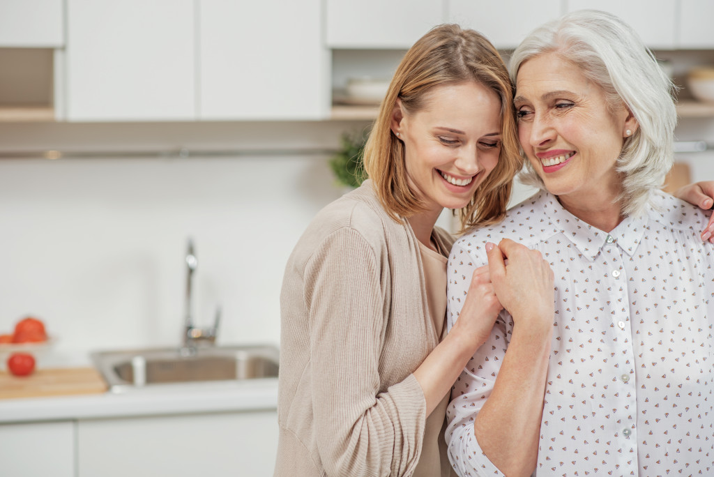 a daughter leaning on her mom in the kitchen