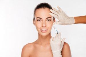 Young woman gets beauty injection in eye area from sergeant