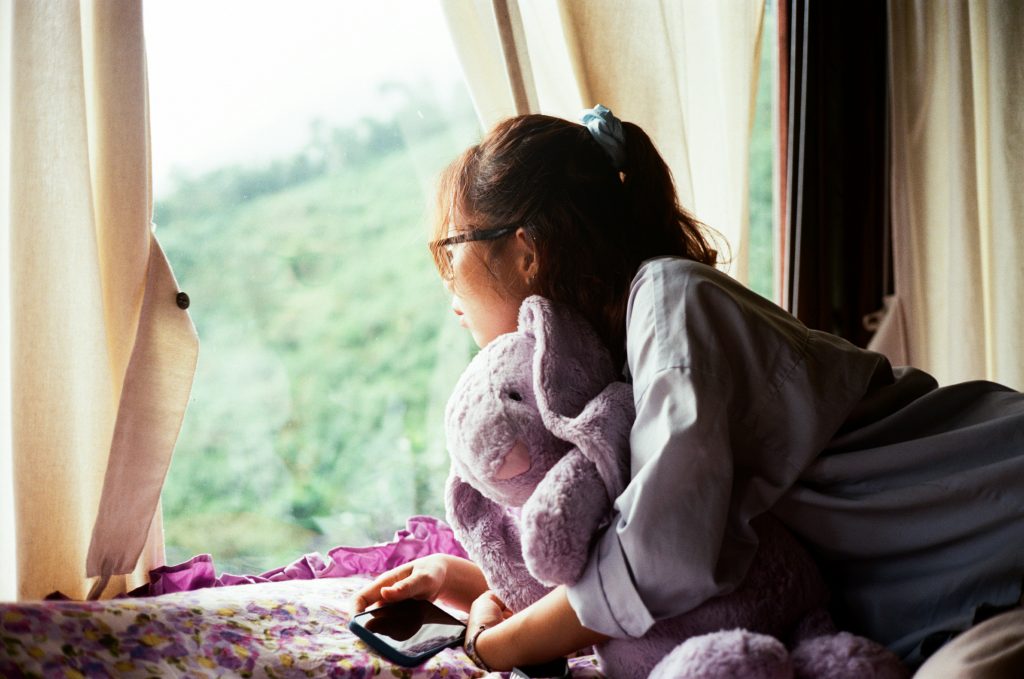 woman in pajamas getting sunlight through a window